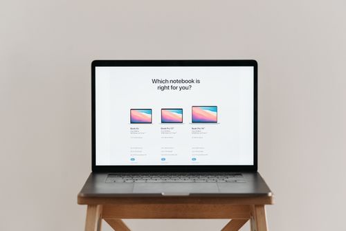 Free An open laptop on a wooden stool showing a notebook comparison chart, ideal for tech-focused imagery. Stock Photo