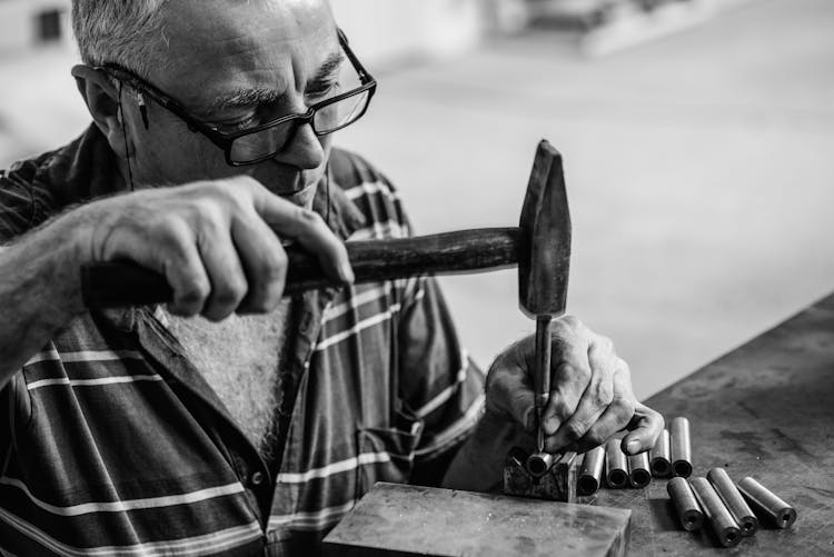 Man In A Checkered Shirt Hammering A Nail