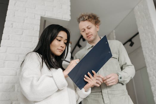 Asian woman signing for package delivery indoors, interacting with courier.