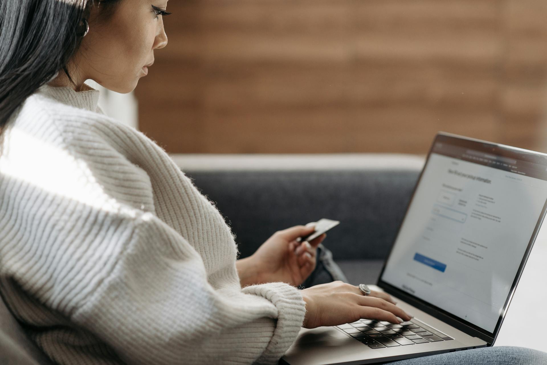 Woman in White Sweater Entering Card Details into Laptop