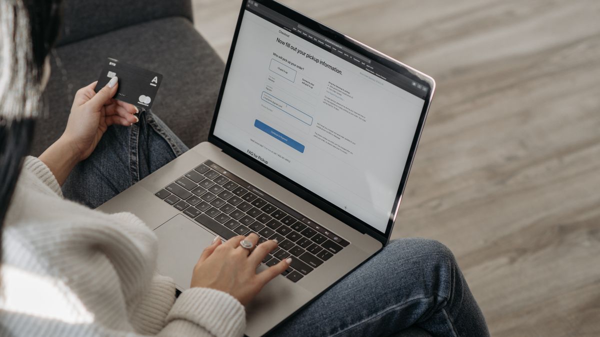 Evde dizüstü bilgisayardan online alışveriş yaparken elinde kredi kartı tutan kadın