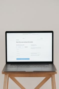 Modern laptop displaying a checkout form against a minimalist beige backdrop.