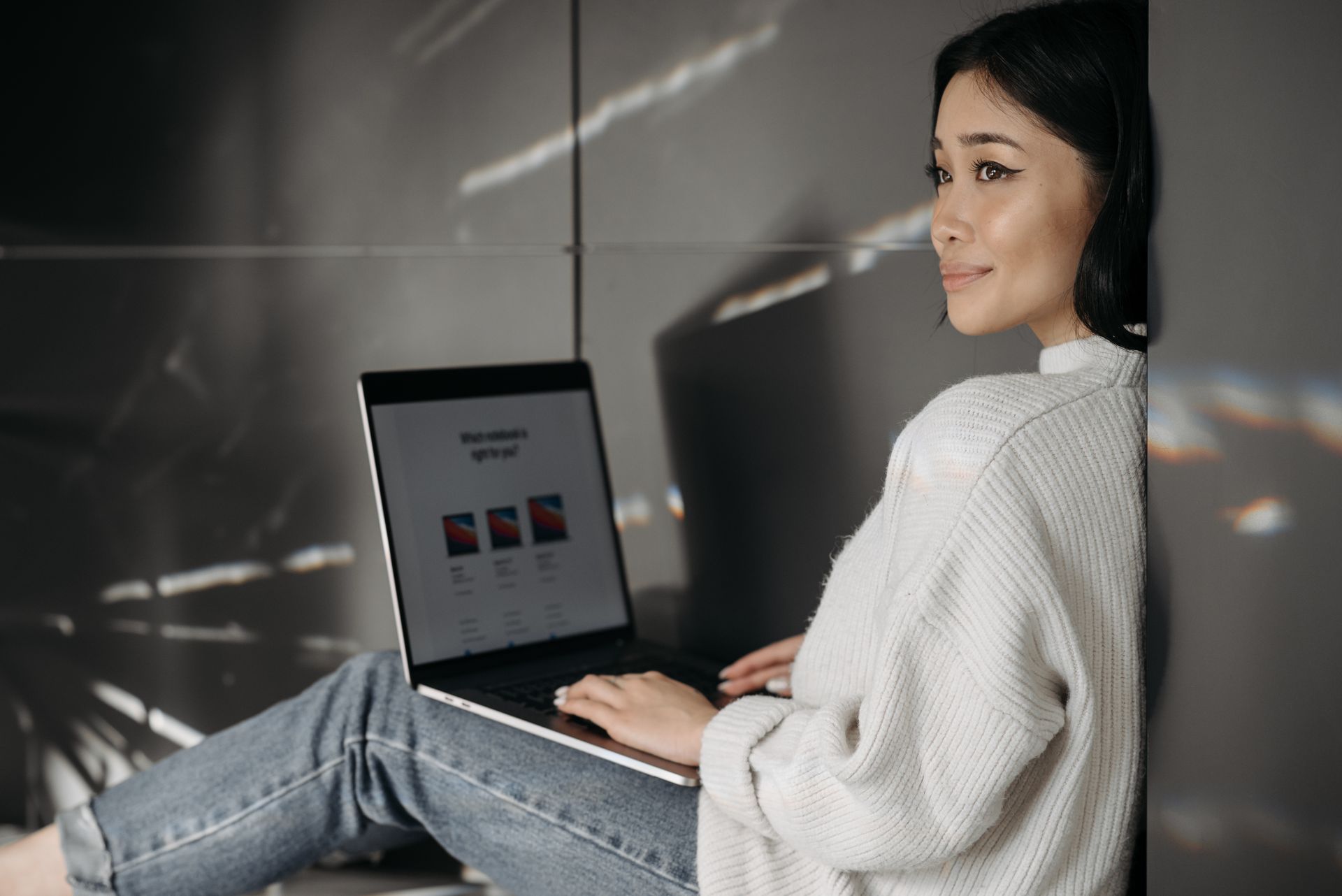 Smiling woman sitting indoors, shopping online with a laptop. Perfect for digital lifestyle themes.