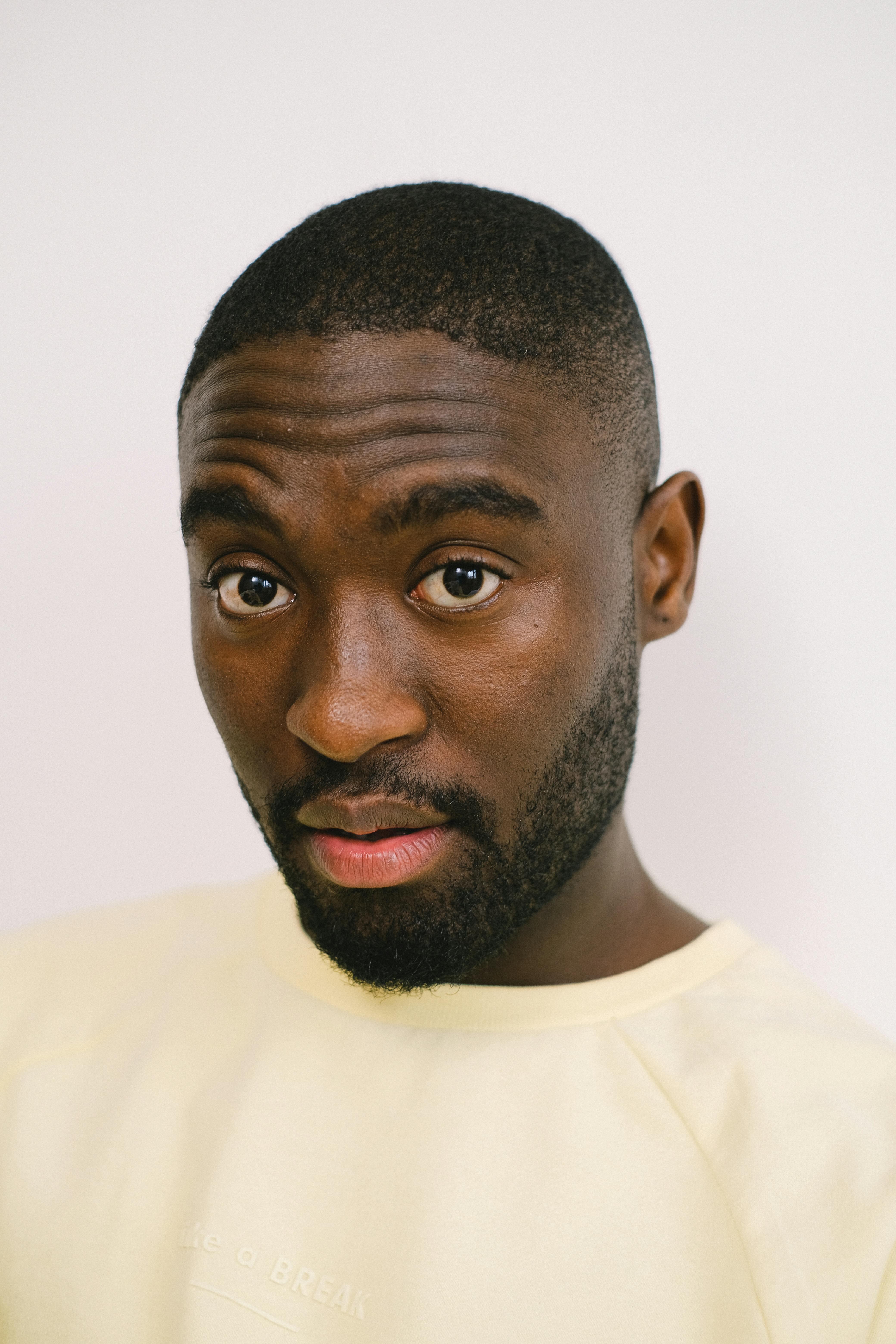 Close-up portrait of a man with a neutral white background, showcasing expression and style.