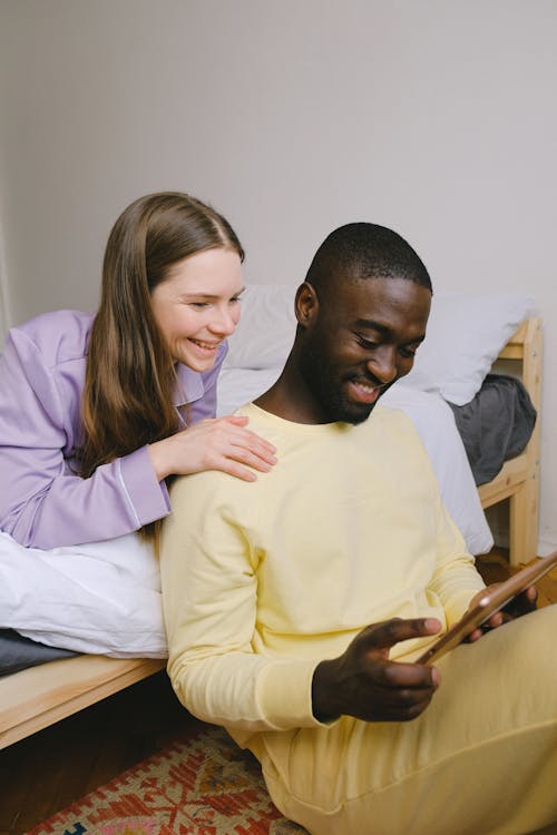 Couple Wearing Pajamas Smiling while Using Digital Tablet