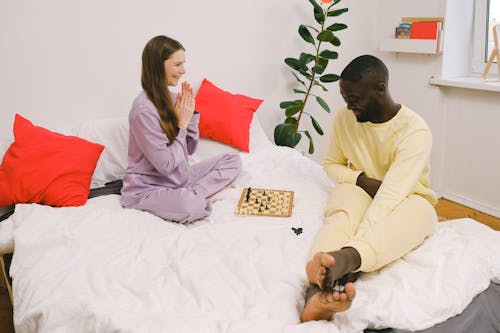 Free Couple in Pajamas Playing Chess in the Bed Stock Photo