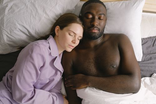 Free Top view of woman in nightwear and African American man sleeping together on comfortable bed in light bedroom at home Stock Photo
