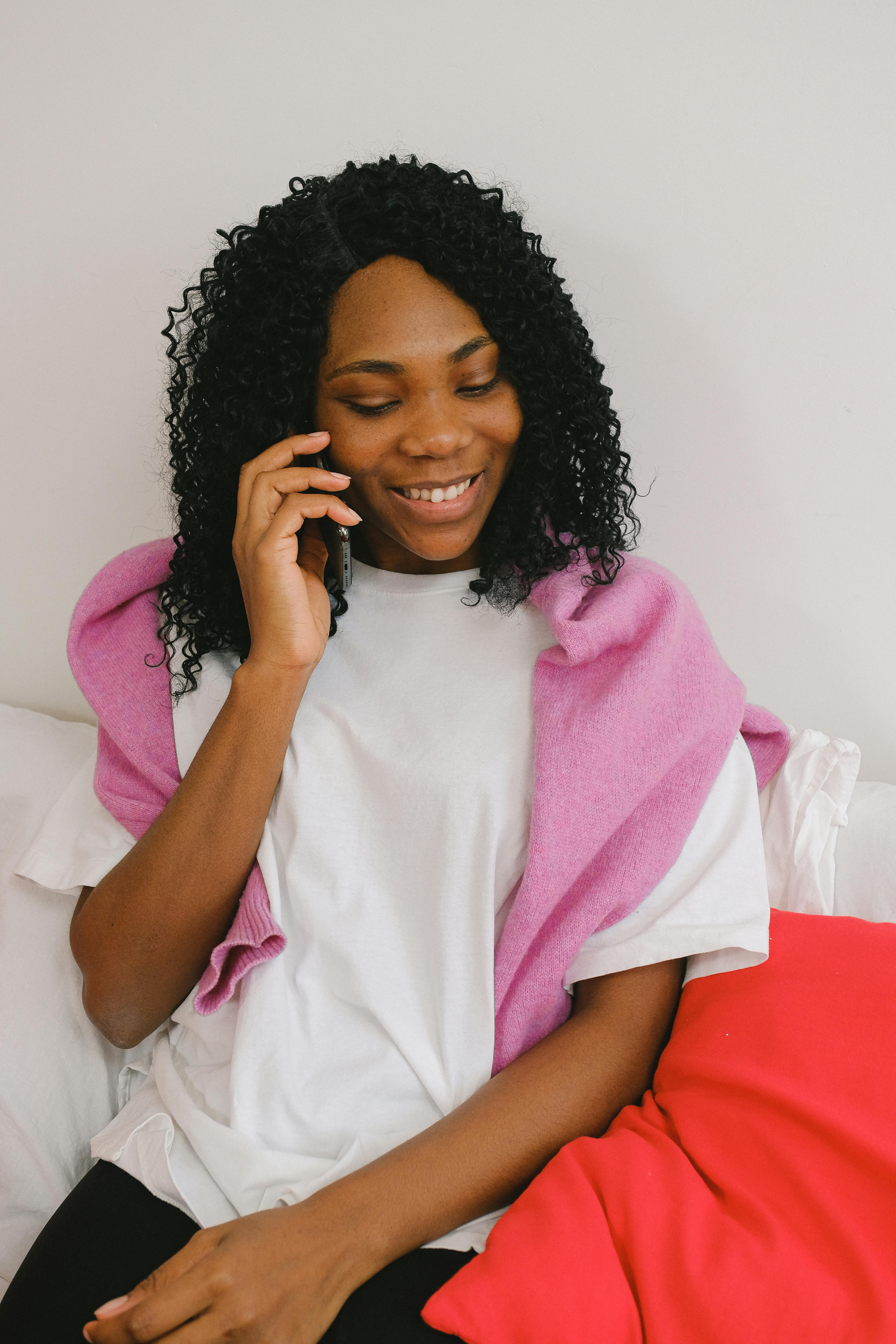 cheerful black woman speaking on smartphone