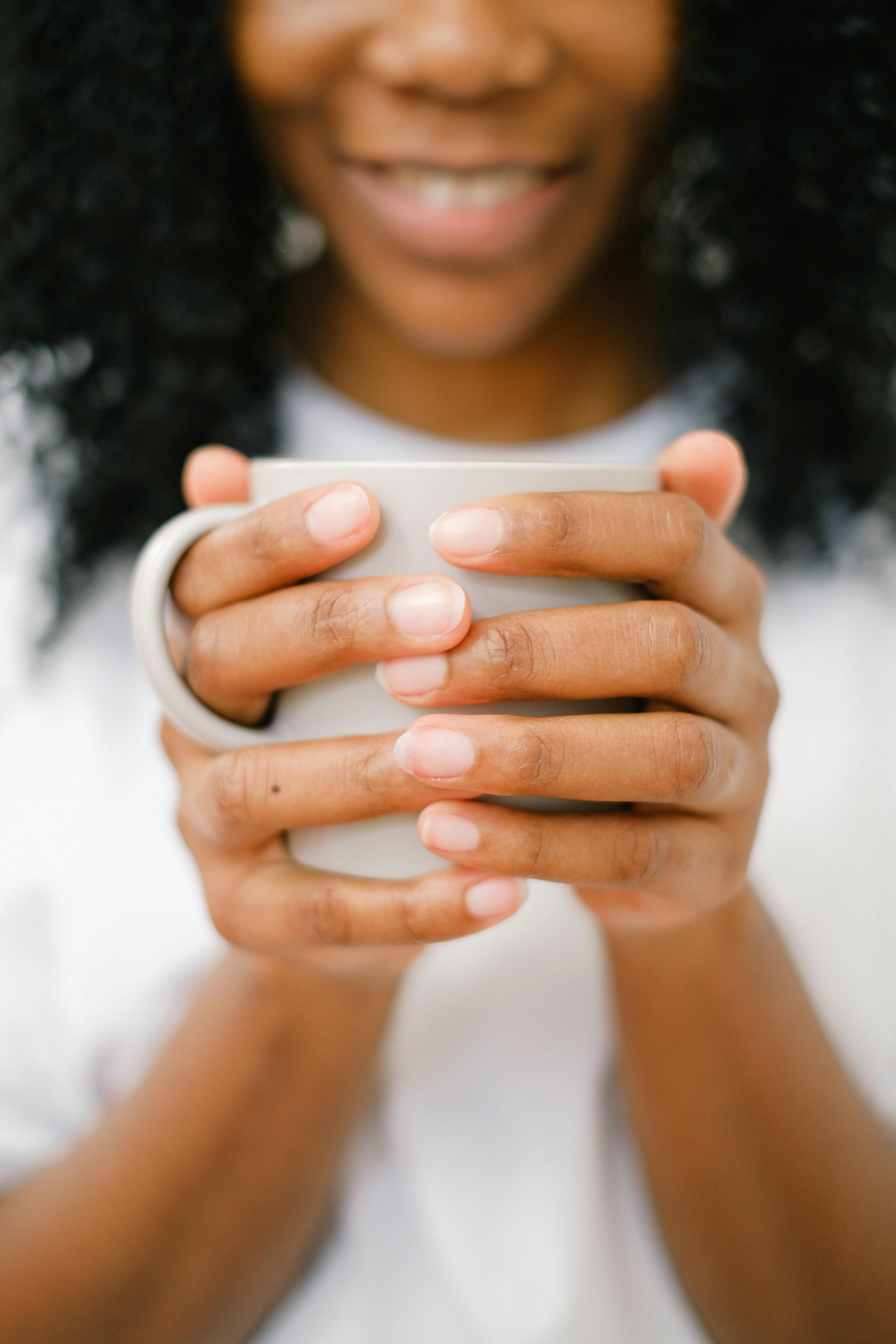 black positive woman with hot cup of coffee smiling