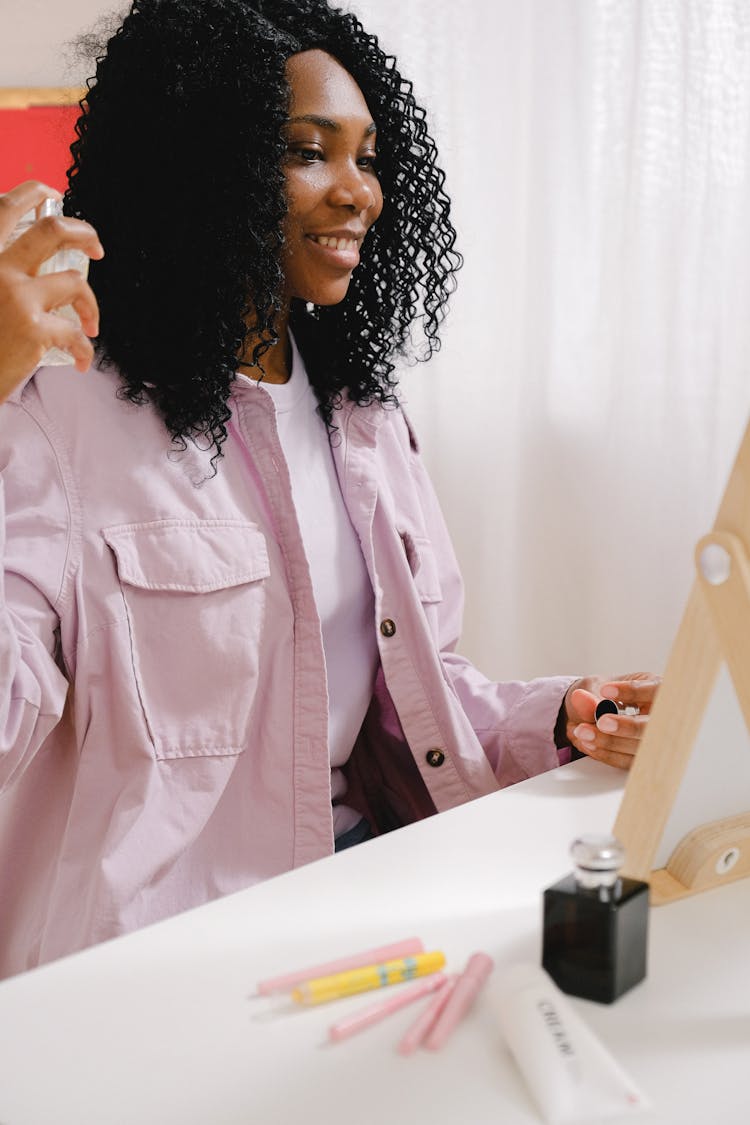 Glad Black Woman Spreading Fragrant Perfume At Table