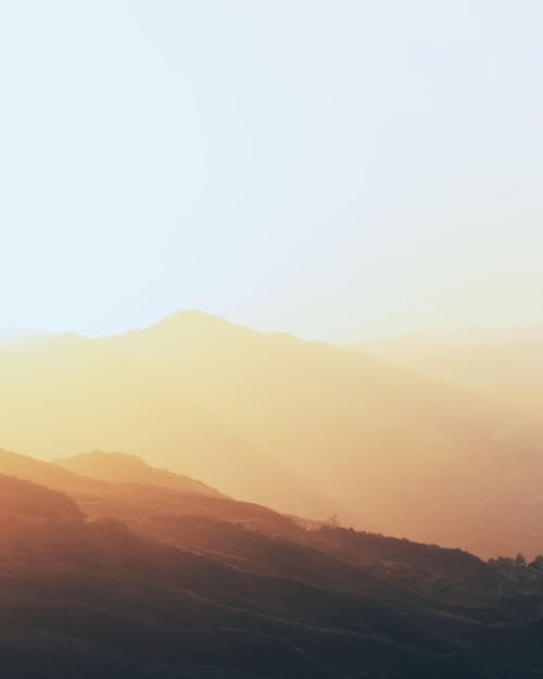 Bright orange foggy sunrise over rough hills