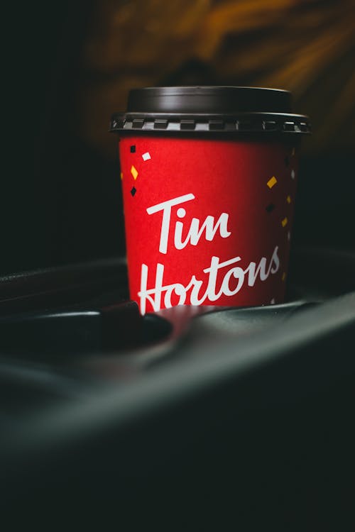 Free Hot coffee in red paper cup with black lid placed in car drink holder on blurred background Stock Photo