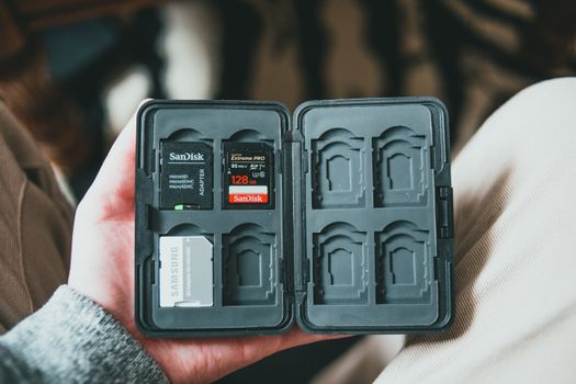From above of crop anonymous male holding memory cards in black case on blurred background