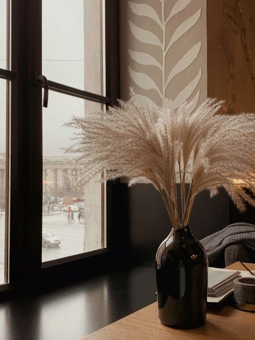 Free Ceramic vase with bunch of Cortaderia selloana grass on wooden table with documents in cafe Stock Photo