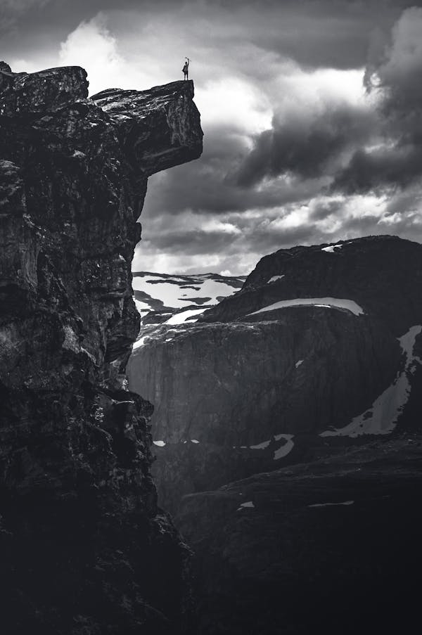 Grayscale Photo of Rocky Mountain Under Cloudy Sky