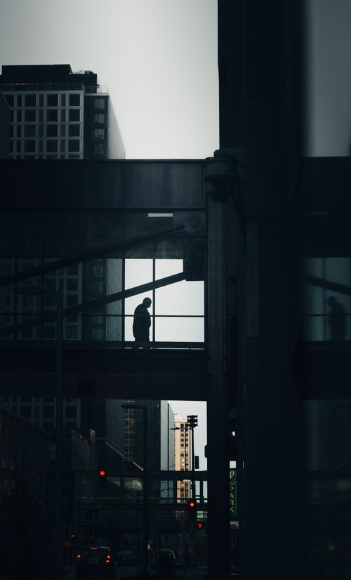 Free A solitary silhouette on a Minneapolis skyway bridge at twilight, framed by urban architecture. Stock Photo