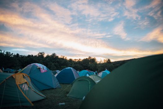 Peaceful campsite with colorful tents and a vibrant sunset sky.
