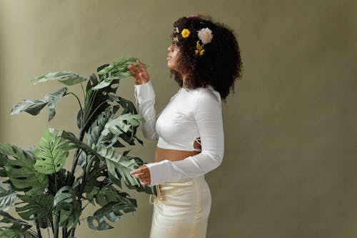 Woman in White Long Sleeve Crop Top Holding Green Plant