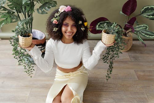 Woman Holding Potted Plants while Sitting on the Floor