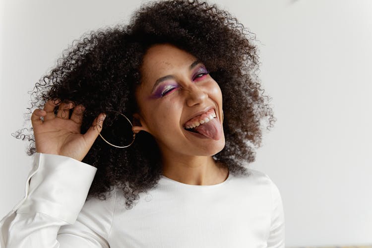 Portrait Of A Woman With Purple Eye Shadows Sticking Out Tongue