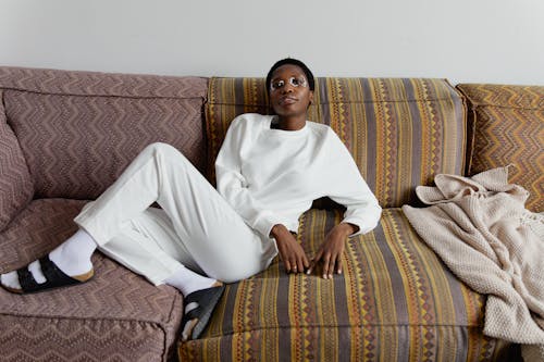 Photo of a Woman Wearing White Clothes Sitting on the Couch