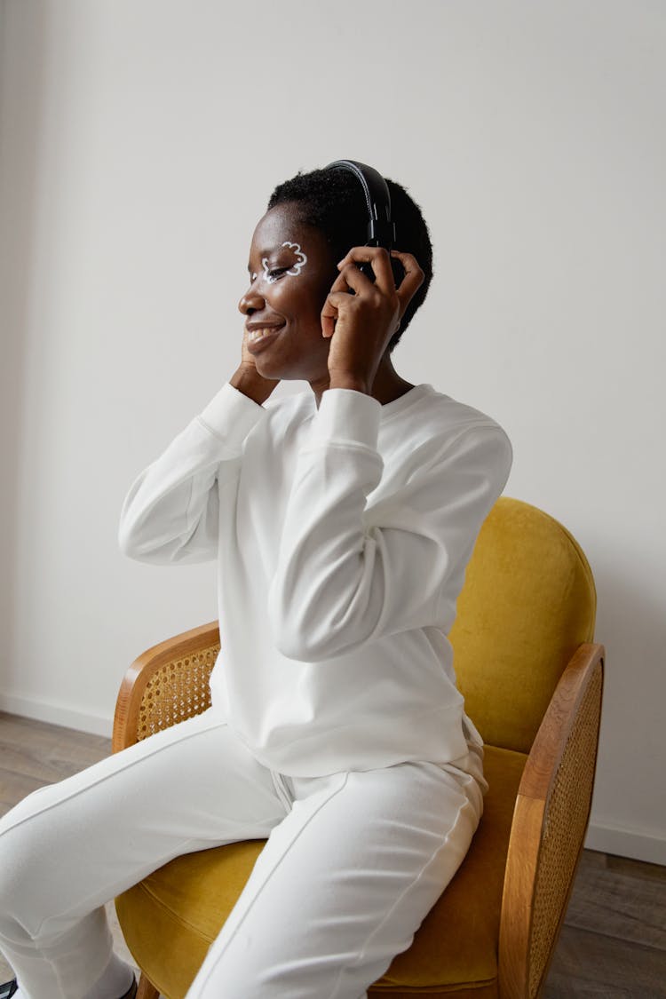 A Woman Wearing White Clothes Listening To A Headphone