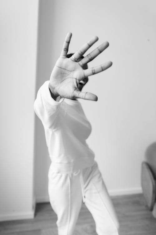 Grayscale Photo of Person's Hand Extended Forward Covering Her Face 