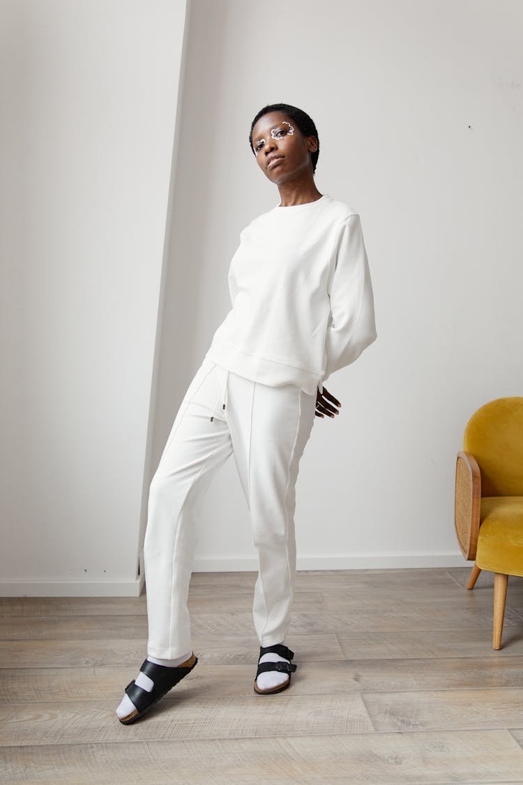 Woman In White Sweatshirt And Pants Standing Near Chair 