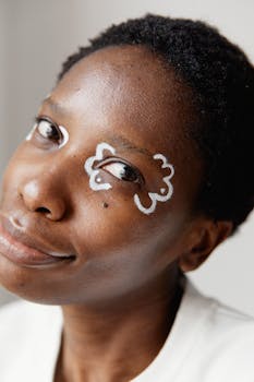 Close-up portrait of a smiling woman with creative white face art on her eyes.