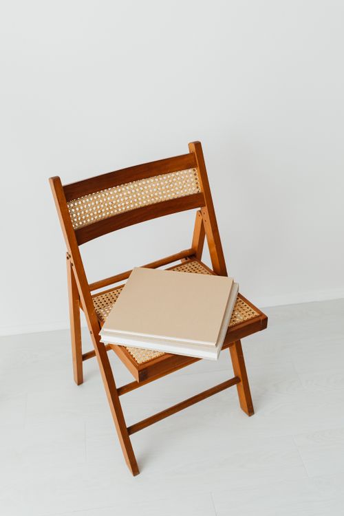 Free Stylish wooden folding chair with books neatly stacked on a minimalist background. Stock Photo