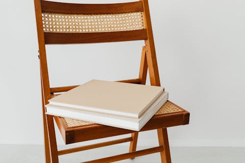 White Books on Top of Brown Chair