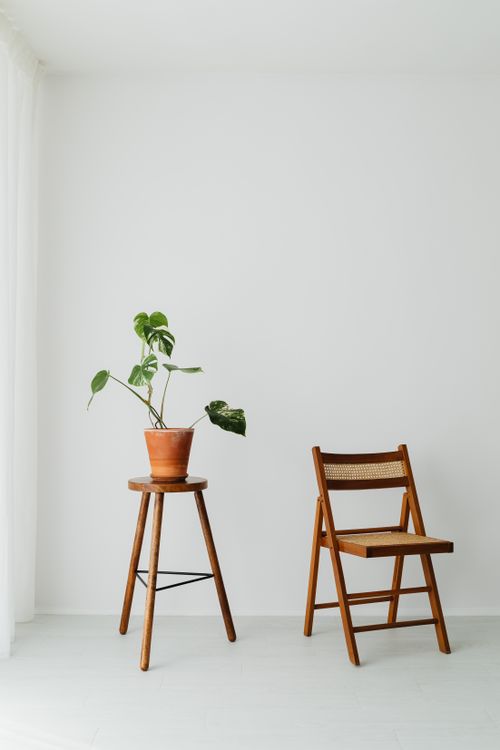 Free Simple interior design featuring a wooden chair and potted plant against a white wall. Stock Photo