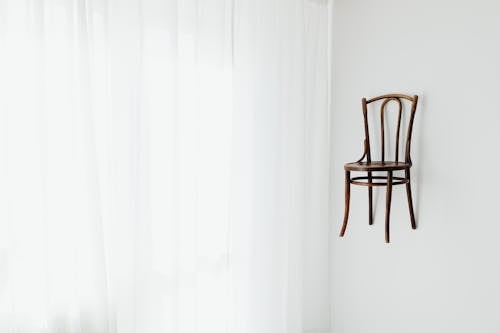 Brown Chair Hanging on Wall Beside Curtain 