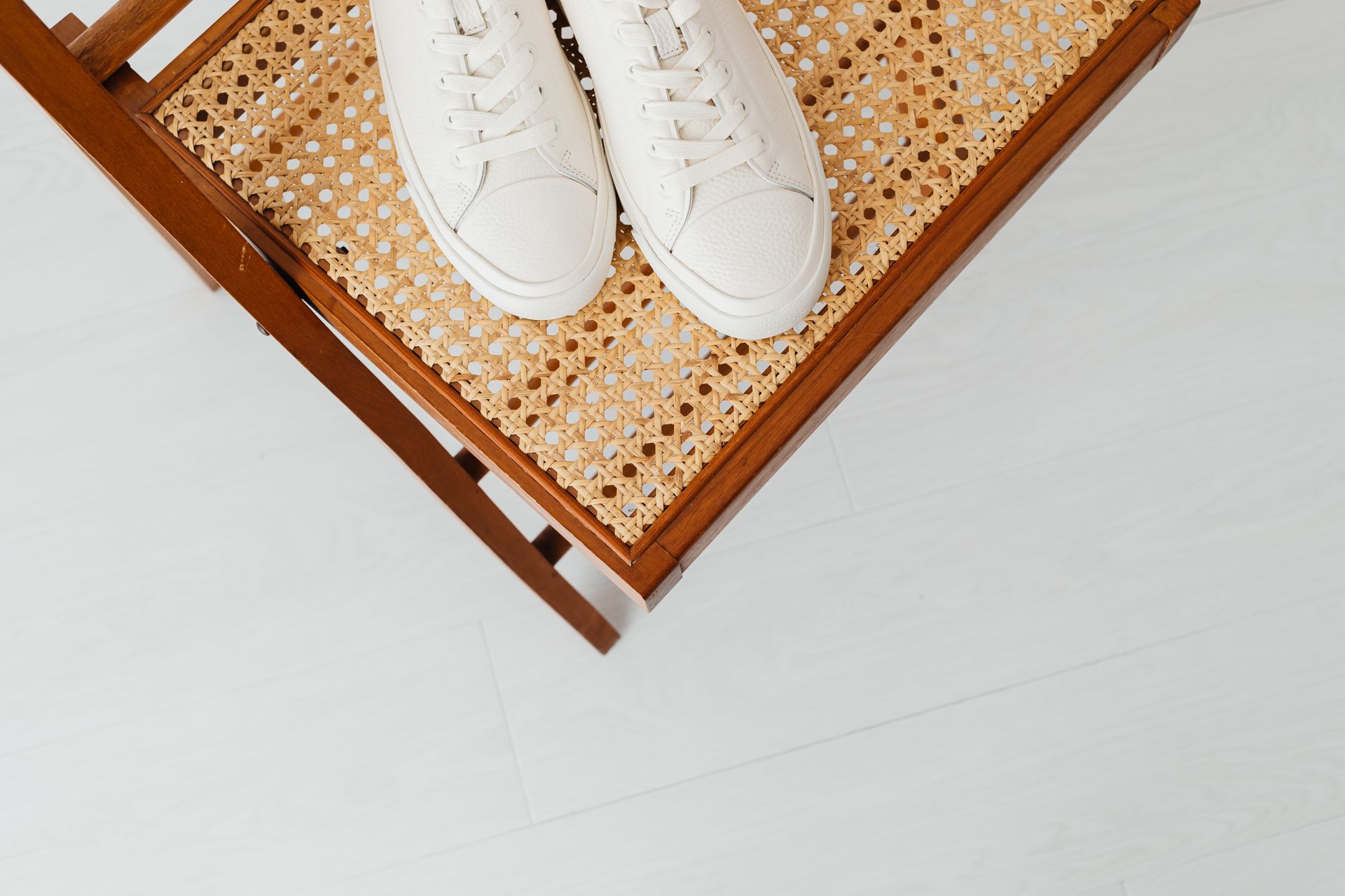 White sneakers placed on a cane chair, offering a minimalist and modern aesthetic with ample copy space.