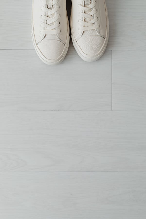 Top Close-up View of White Sneaker Shoes on Light Floor Panels