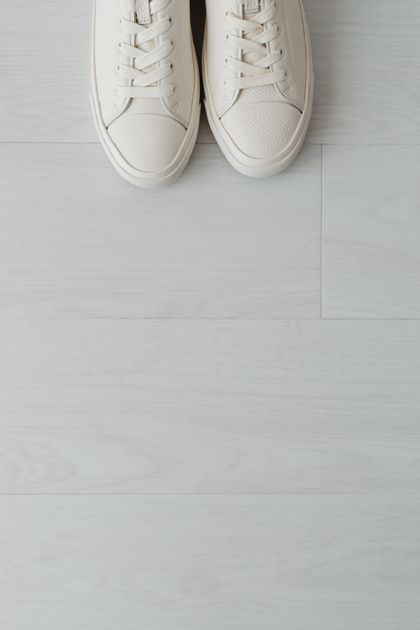 Cream leather sneakers photographed from above on a pale floor — photo by Kaboompics.com on Pexels