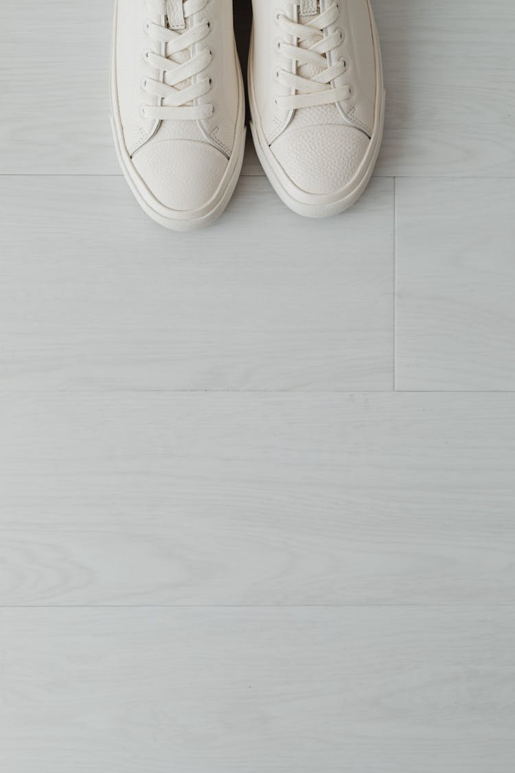 Top Close-up View Of White Sneaker Shoes On Light Floor Panels