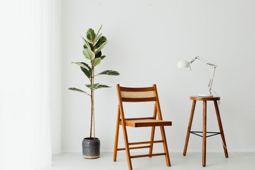 Stylish minimalist interior setting with a folding chair, desk lamp, and potted plant on wooden stool.