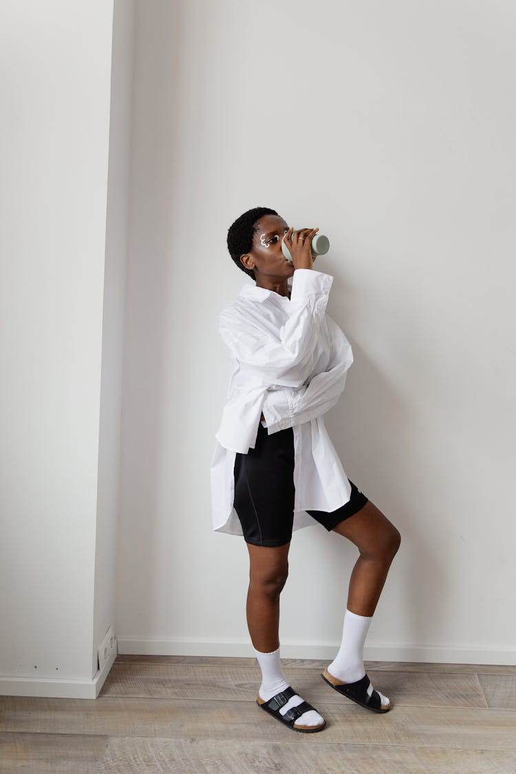 Woman In White Long Sleeves Standing While Drinking From A Tumbler