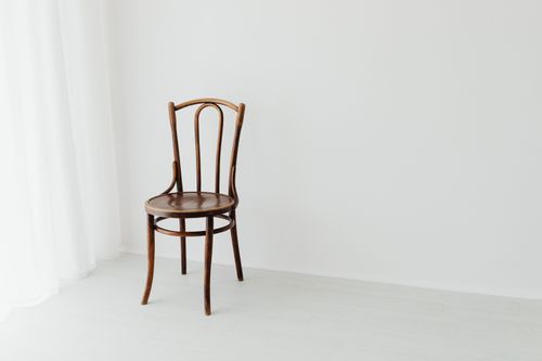 Free A simple wooden chair sits in a bright, minimalist interior with a white background. Stock Photo