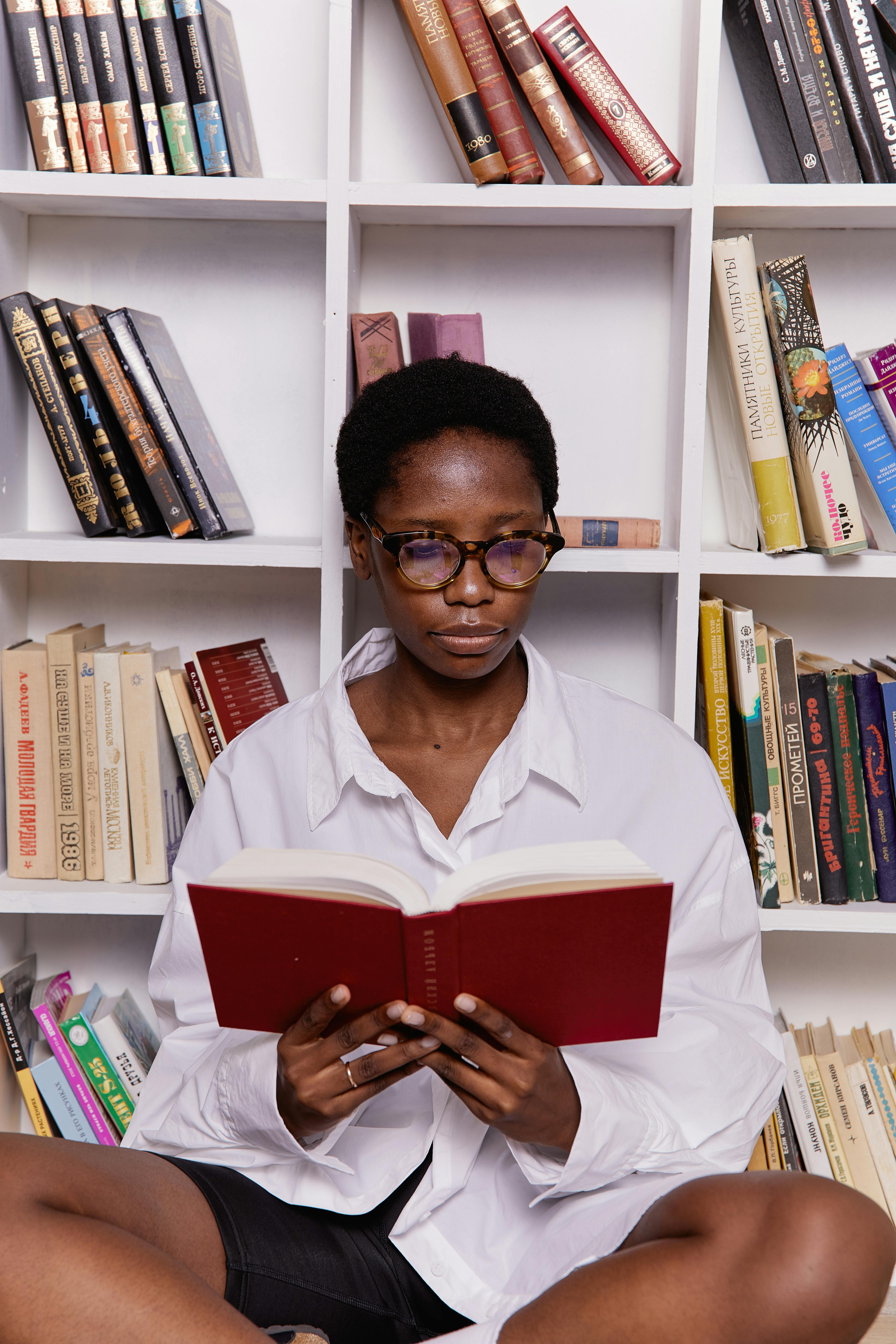 woman reading a book in front of the book shelves