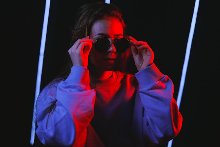 Woman Wearing Shades In A Dark Room Illuminated In Red Light