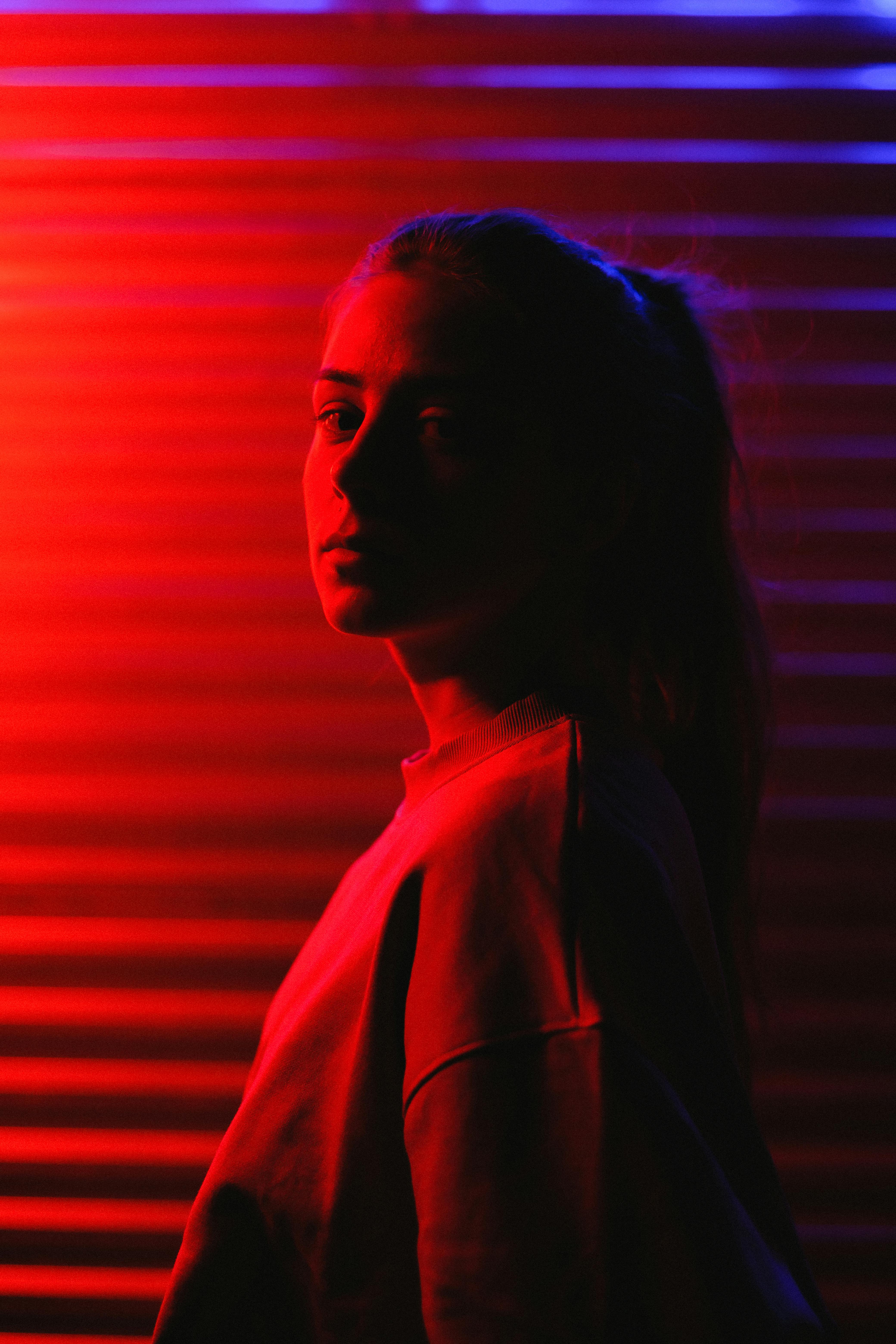 Woman Illuminated in Red Light Looking at Camera · Free Stock Photo