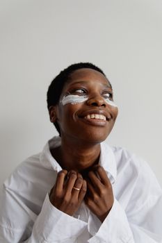 A joyful African American woman adorned with face paint, wearing a white shirt and smiling warmly.