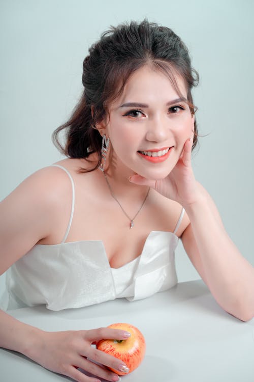 Woman in White Spaghetti Strap Top with Hand on Face