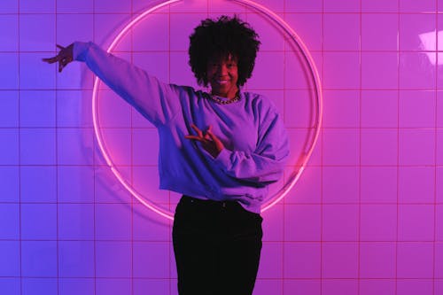 Smiling black female dancing in room with neon lights