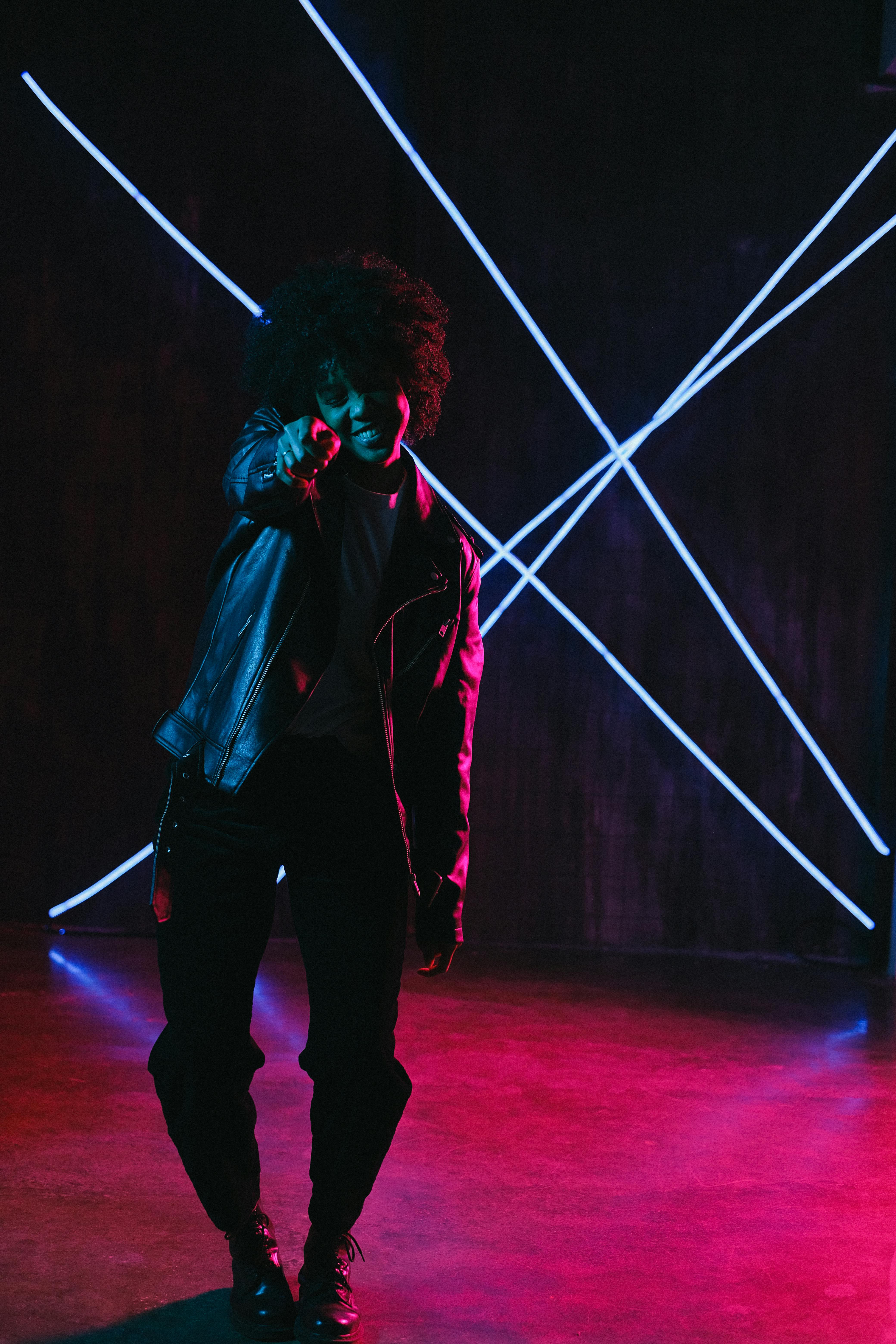 cool ethnic teen on street in neon light at dusk