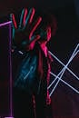 Black teen showing stop gesture in neon light at dusk