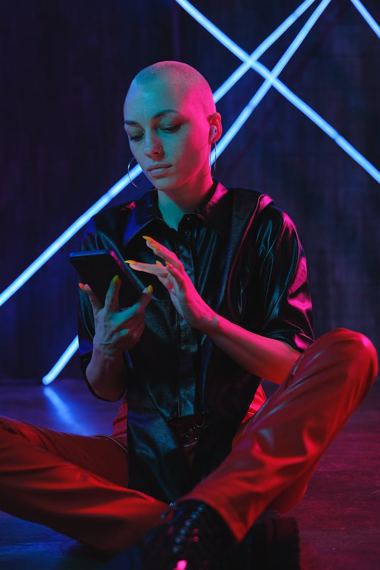 Emotionless Bald Woman Using Smartphone On Studio Floor