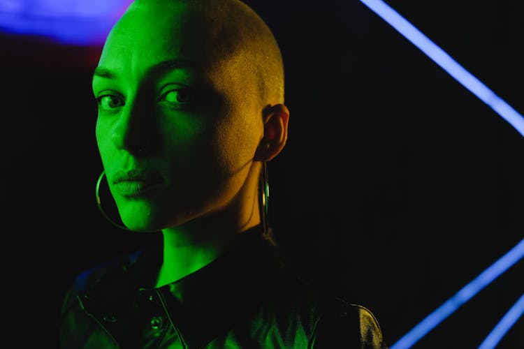 Crop Bald Woman Covered With Green Neon Light